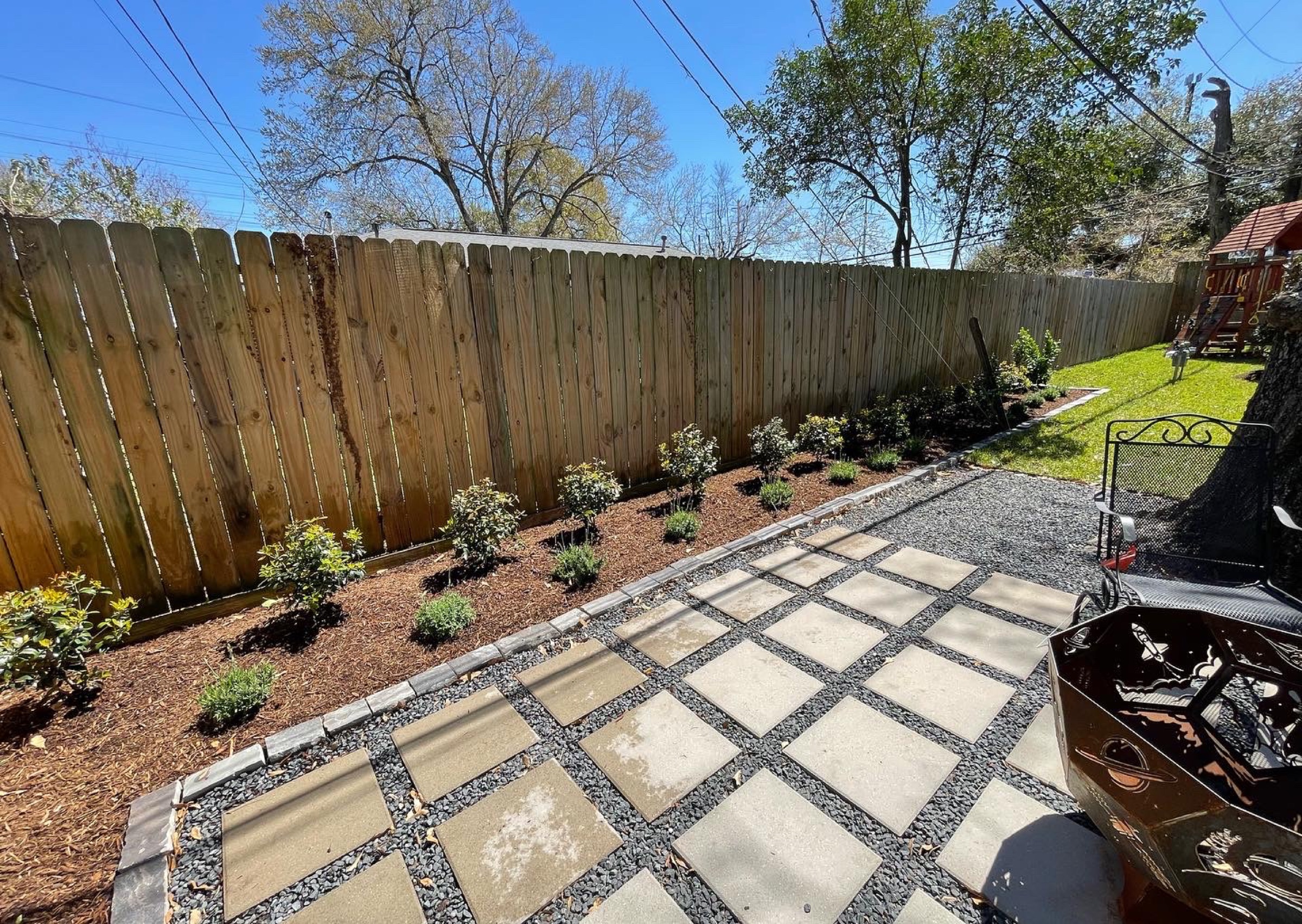 Paver patio in gravel with a planted Houston fence line
