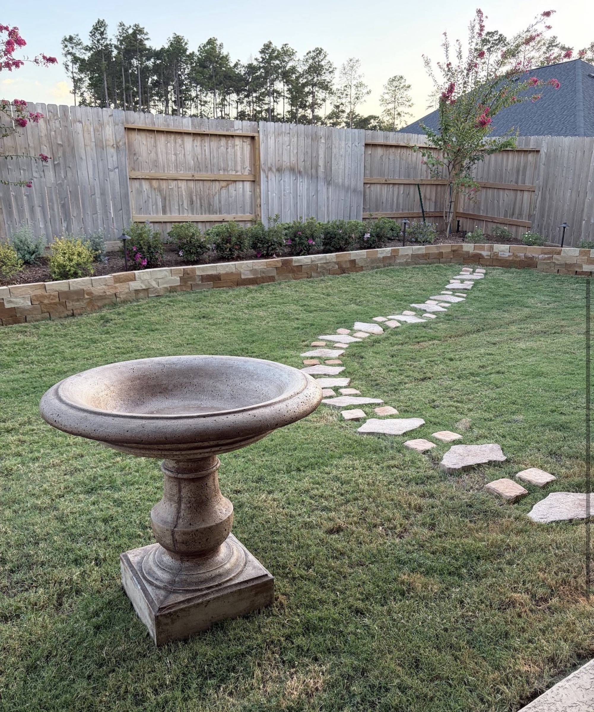 Houston backyard with limestone retaining wall and birdbath