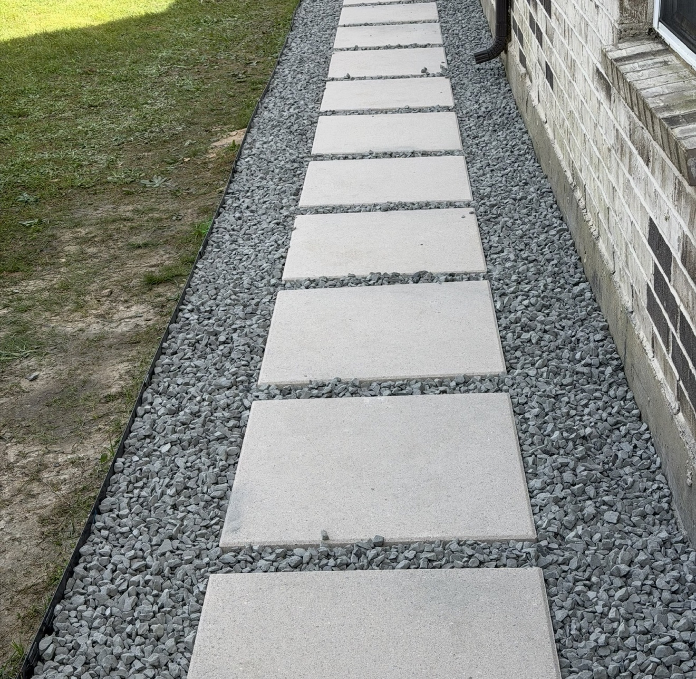 Paver stepping stones in gravel along a Houston house