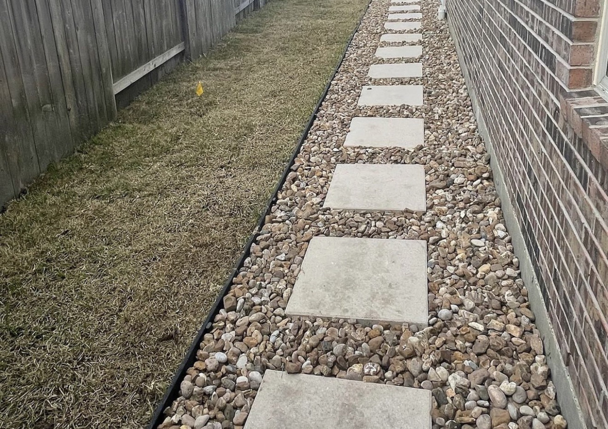 Square pavers in river rock along a Houston house