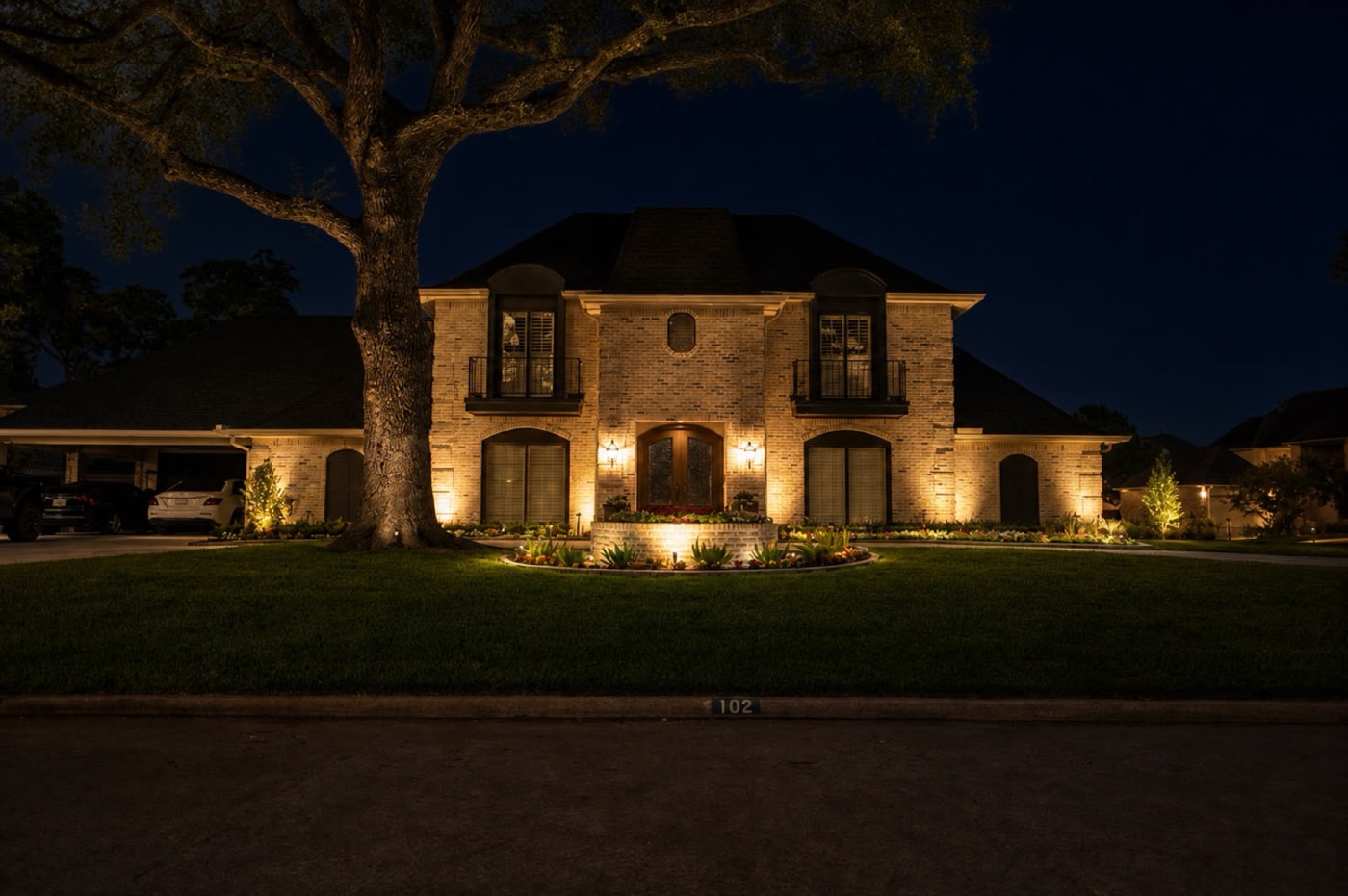 Brick Houston home with landscape lighting after dark