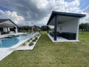 Modern outdoor space with pool, landscaped area featuring white stones and greenery, and covered seating area, highlighting landscaping design options for Houston homes.